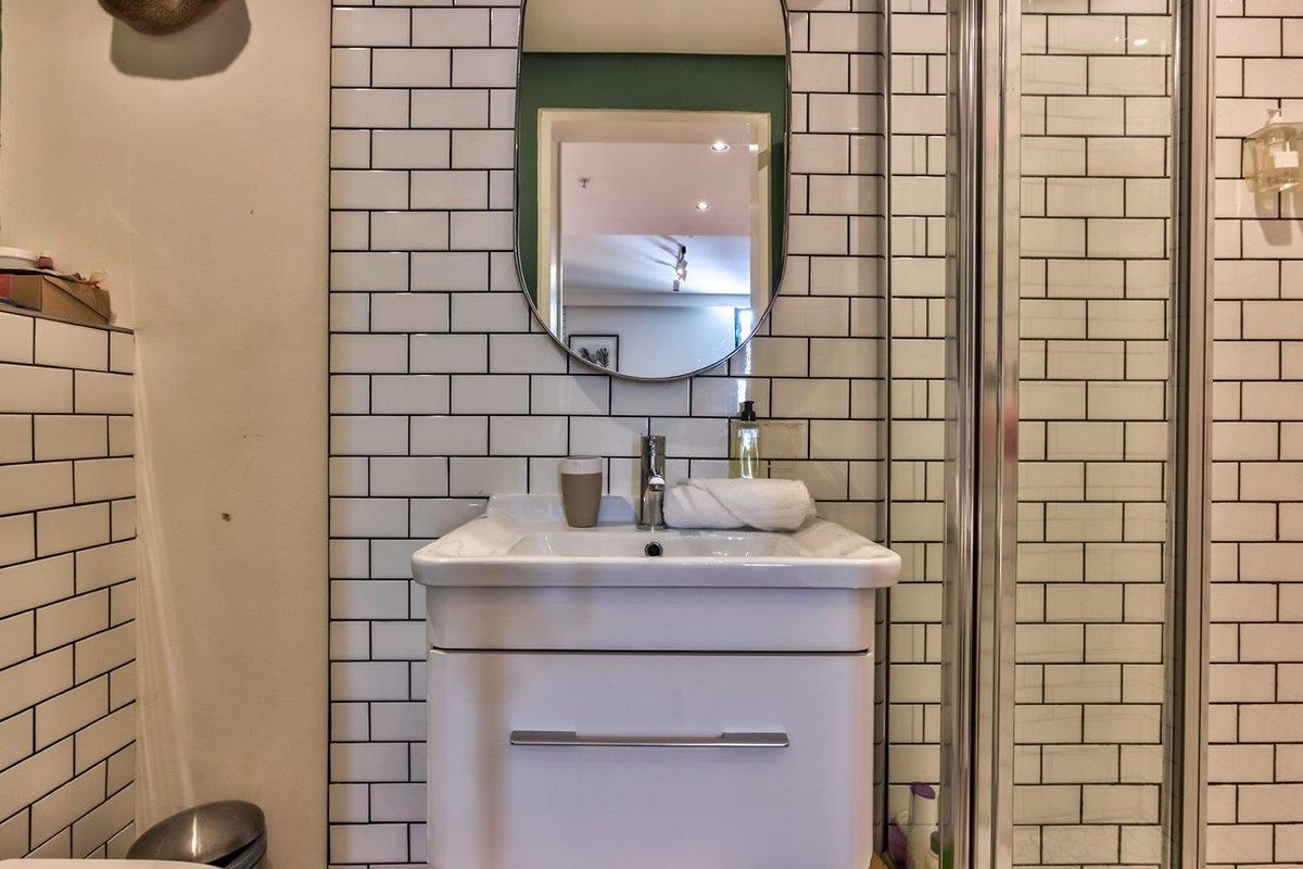 A modern bathroom featuring white subway tile wall cladding, a vanity basin with chrome mixer tap, and a glass shower enclosure.