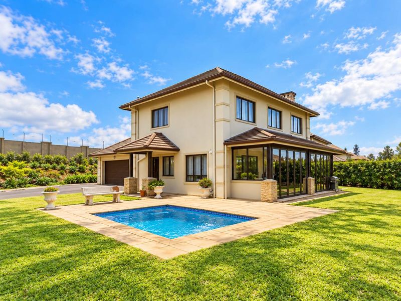 Rear view of a well-maintained townhouse featuring a private swimming pool, paved patio area, and an enclosed sunroom with large glass doors.