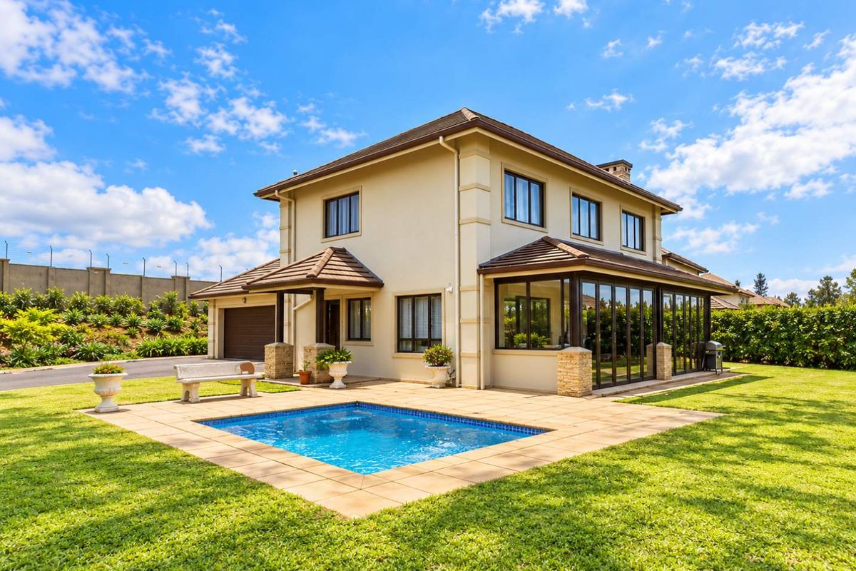 Rear view of a well-maintained townhouse featuring a private swimming pool, paved patio area, and an enclosed sunroom with large glass doors.