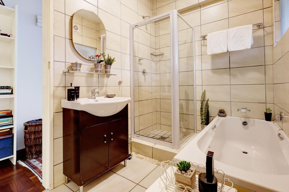A well-maintained bathroom featuring a vanity cabinet, a separate shower enclosure, and a bathtub with neutral wall and floor tiling.