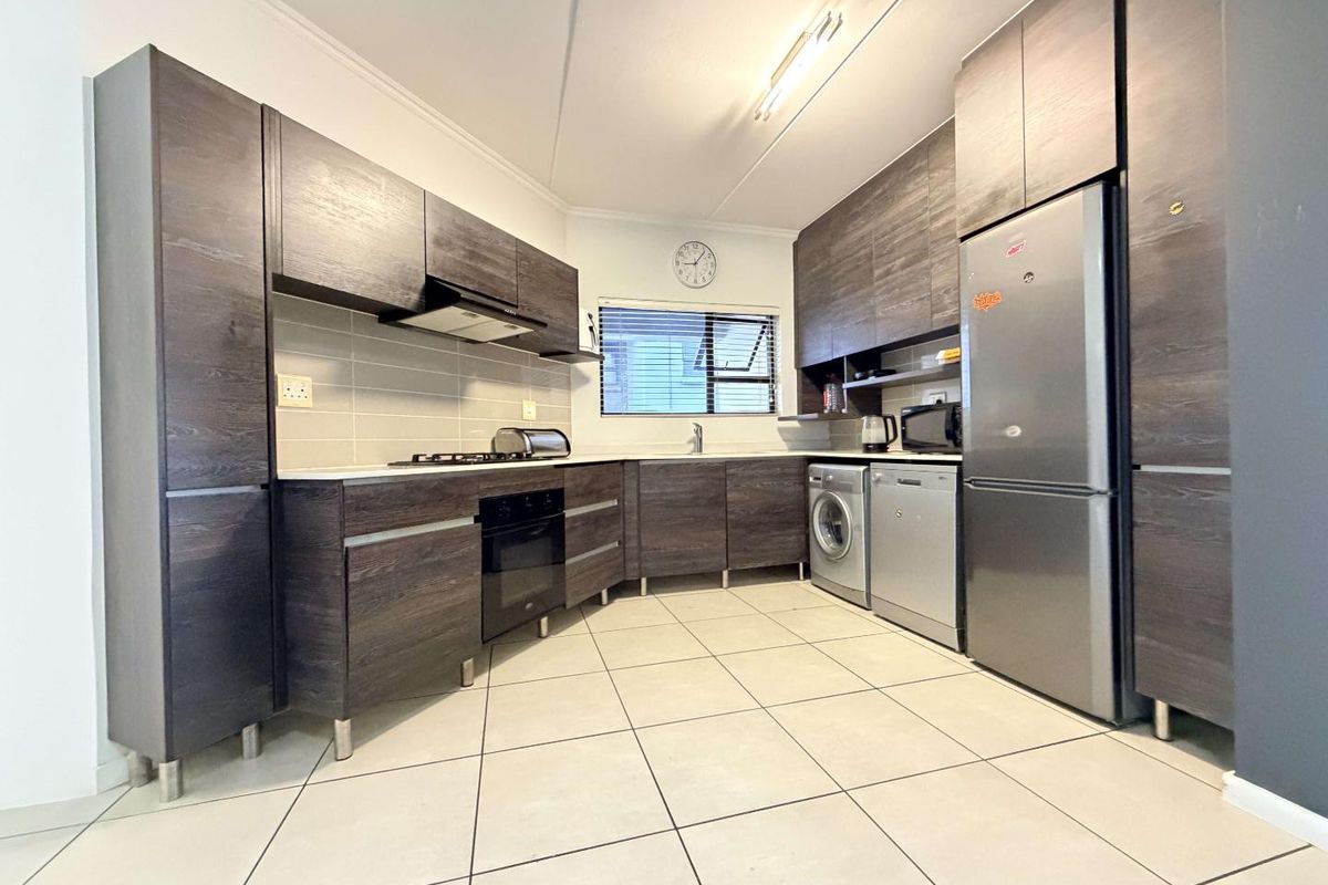 Modern kitchen featuring dark wood cabinetry, tiled flooring, built-in oven, gas hob, and integrated spaces for appliances.