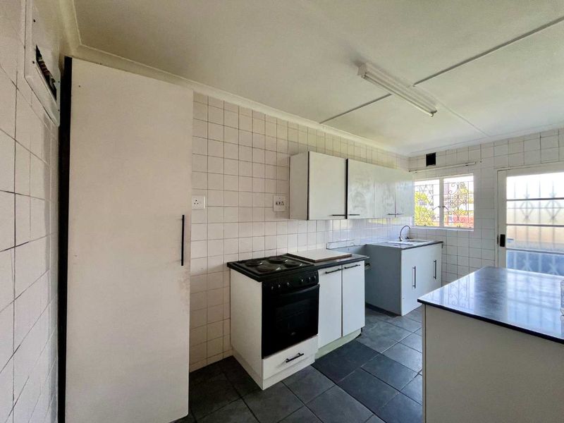 A functional kitchen featuring built-in cabinetry, an electric stove, oven, and tiled finishes, offering a blank canvas for potential modern updates.