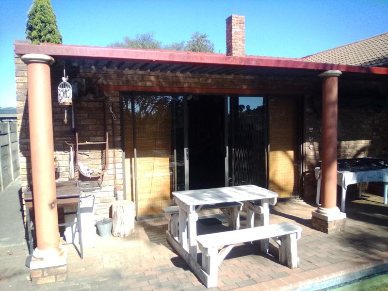 A covered outdoor patio area featuring brick construction, sliding glass doors, and a brick chimney, providing a functional space for outdoor living.