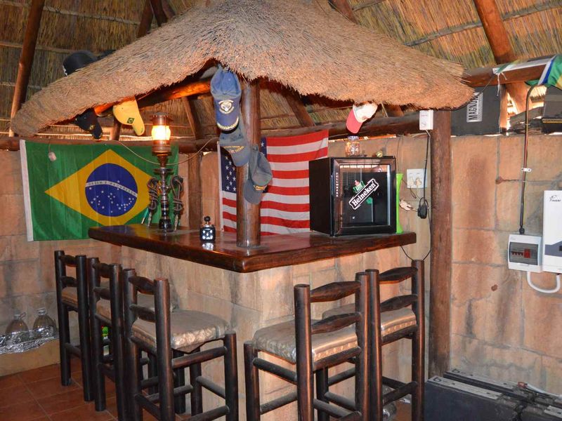 A rustic indoor bar area featuring a thatched roof structure, built-in bar counter, and integrated solar power infrastructure.