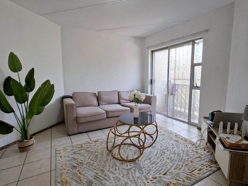A living room featuring ceramic floor tiles and a sliding glass door providing access to an outdoor area.
