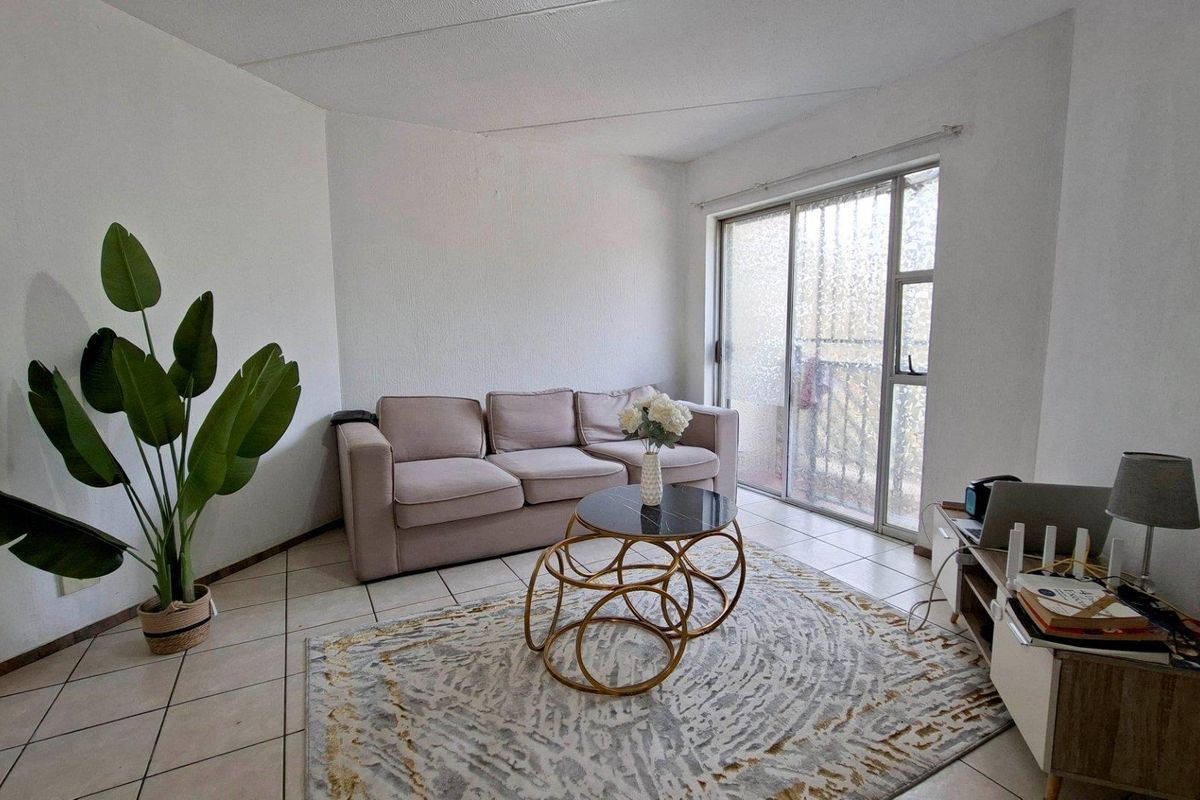 A living room featuring ceramic floor tiles and a sliding glass door providing access to an outdoor area.