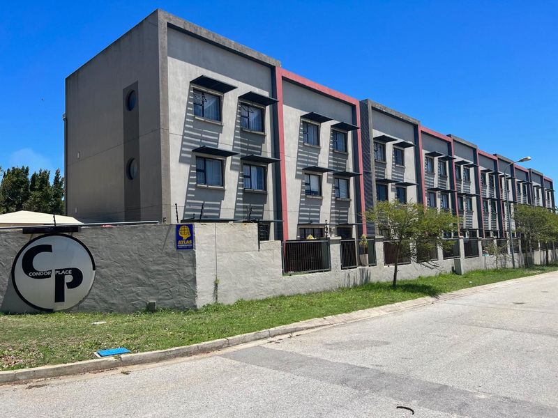 Exterior view of Condor Place apartment complex featuring a modern facade with metal window awnings and secure perimeter walling.