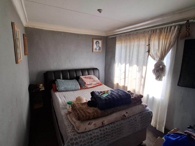 A compact bedroom featuring grey textured walls, ceiling cornicing, and a window with a curtain rail.