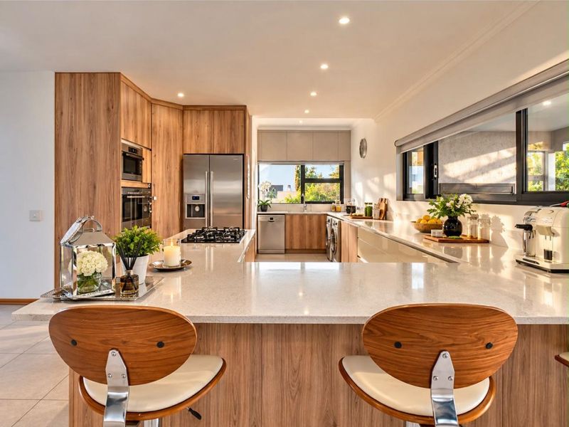 Modern kitchen featuring wood veneer cabinetry, quartz countertops, a central island with gas hob, and high-end built-in appliances in a bright, open-plan layout.