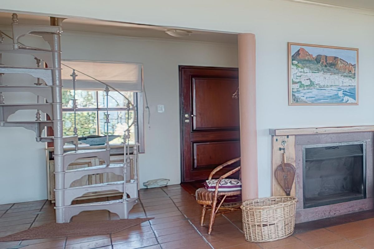 Living area featuring a spiral staircase, a built-in fireplace with stone surround, and terracotta floor tiles leading to a wooden entrance door.