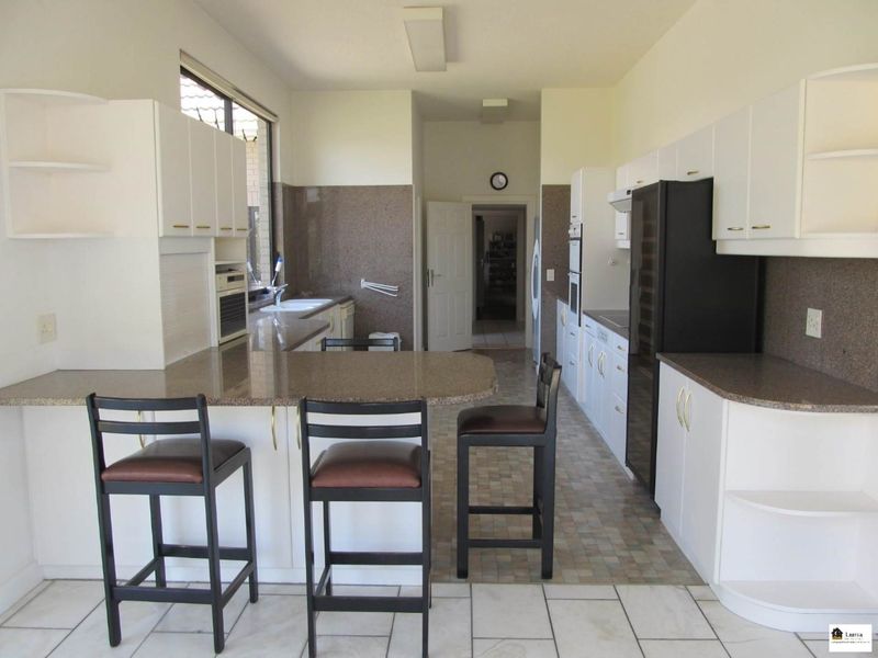 A functional kitchen featuring granite countertops, ample built-in cabinetry, a breakfast bar, and tiled flooring, offering a practical layout for daily use.