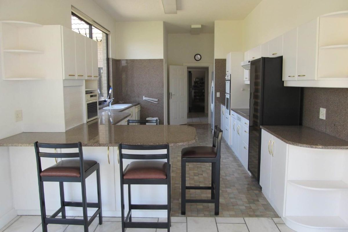 A functional kitchen featuring granite countertops, ample built-in cabinetry, a breakfast bar, and tiled flooring, offering a practical layout for daily use.