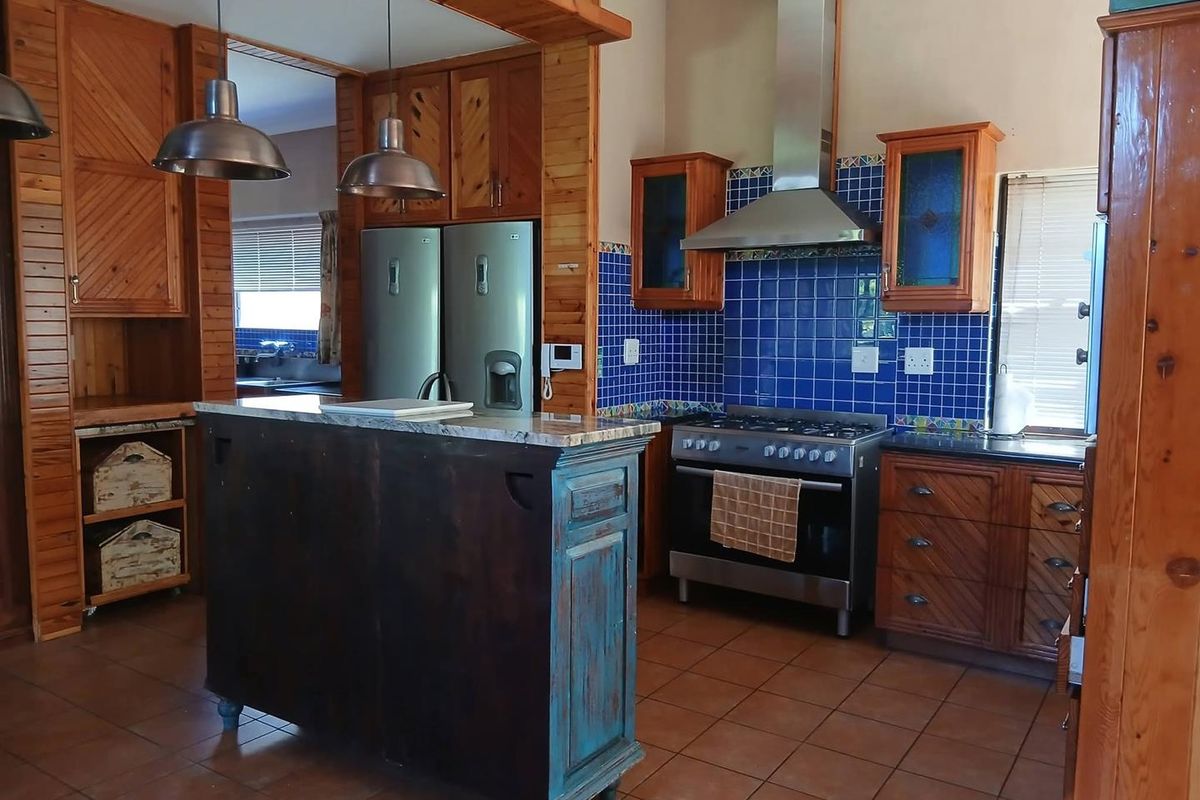 A rustic-style kitchen featuring extensive wooden cabinetry, granite countertops, a tiled backsplash, and a central island, providing a functional and warm cooking space.