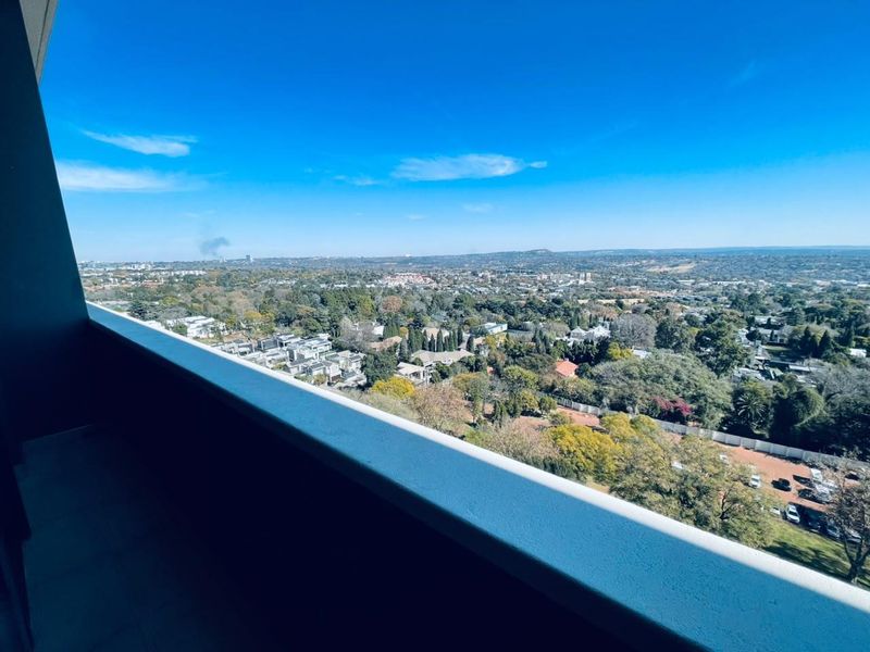 Elevated panoramic view of the surrounding suburban landscape and greenery, captured from a high-rise apartment balcony.