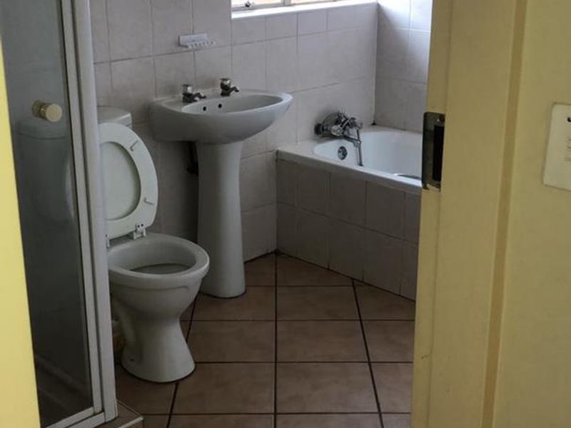 A dated bathroom featuring a pedestal basin, built-in bathtub, and separate shower enclosure with tiled finishes throughout.