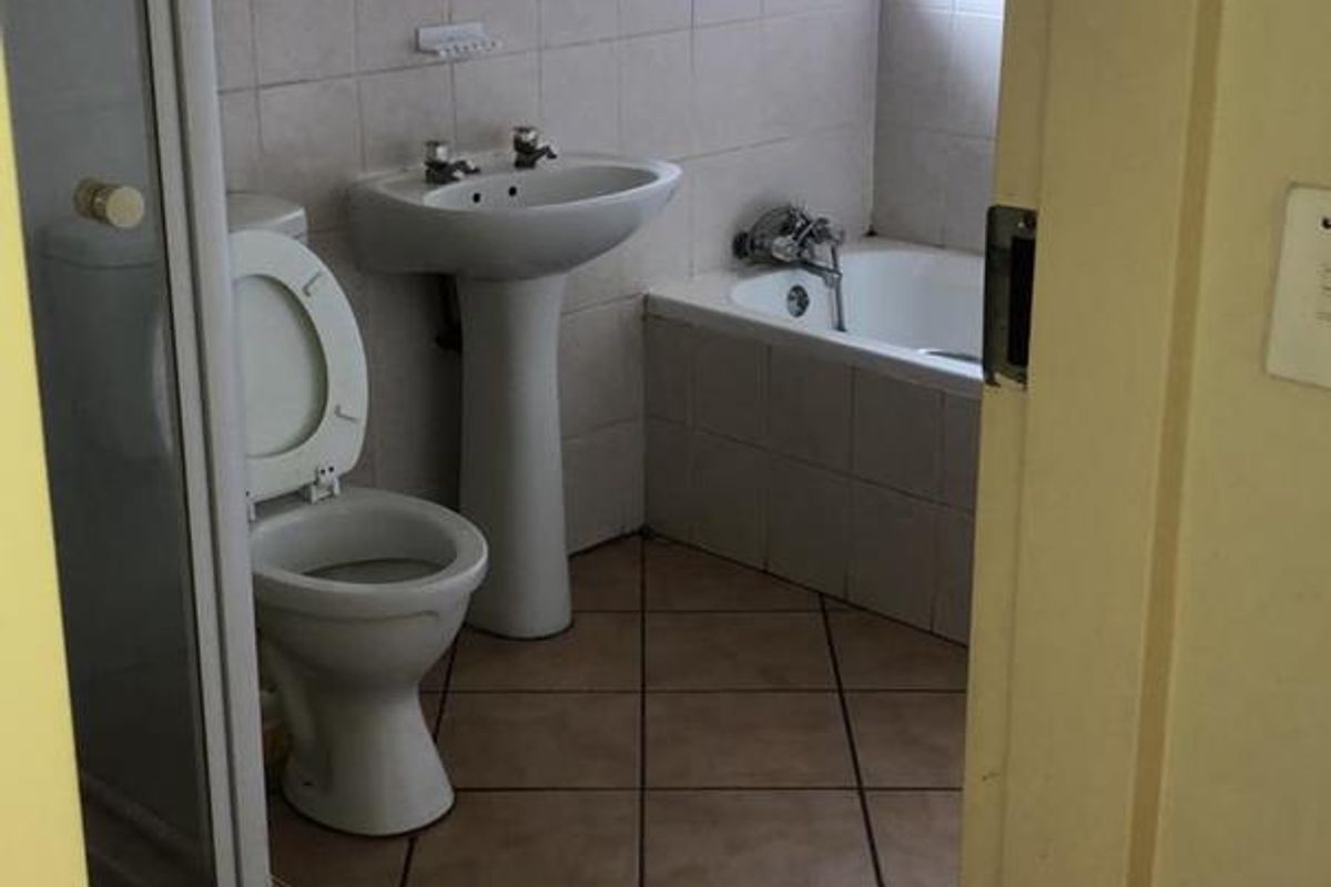 A dated bathroom featuring a pedestal basin, built-in bathtub, and separate shower enclosure with tiled finishes throughout.