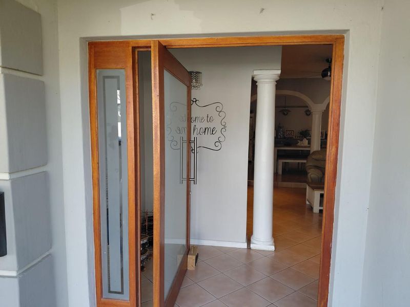 Entrance area featuring a timber-framed glass door, tiled flooring, and a decorative column leading into the main living space.