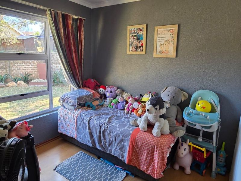 A bedroom featuring a large window with garden views and a built-in cupboard, currently utilized as a child's room.