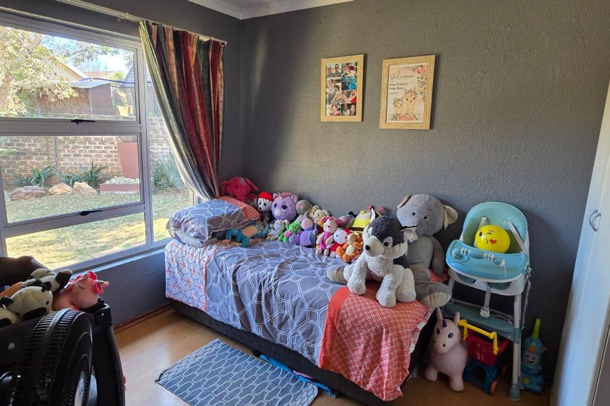A bedroom featuring a large window with garden views and a built-in cupboard, currently utilized as a child's room.