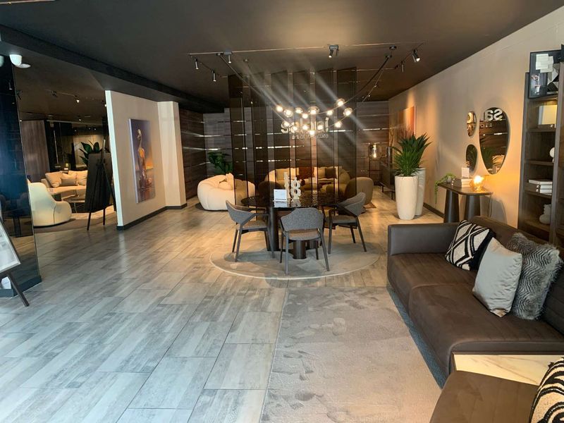 A modern, well-lit open-plan retail showroom space featuring contemporary tiled flooring, track lighting, and a decorative partition screen.
