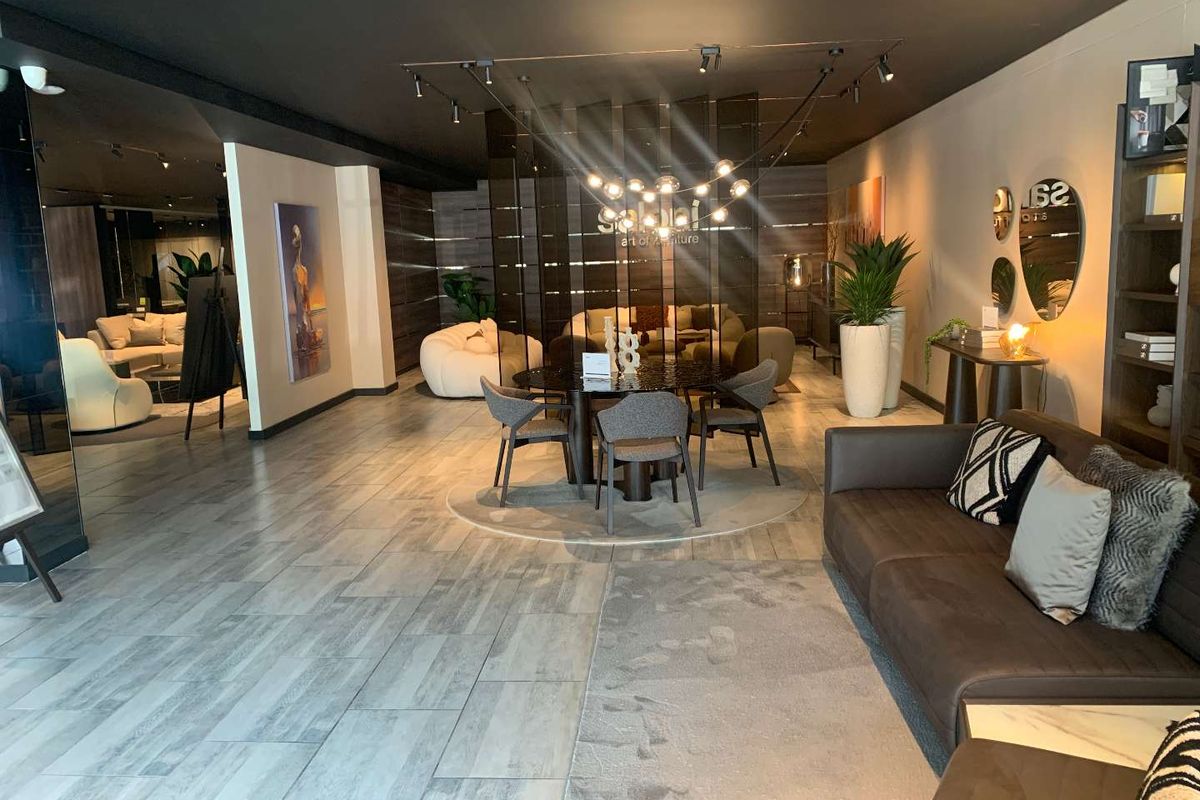 A modern, well-lit open-plan retail showroom space featuring contemporary tiled flooring, track lighting, and a decorative partition screen.