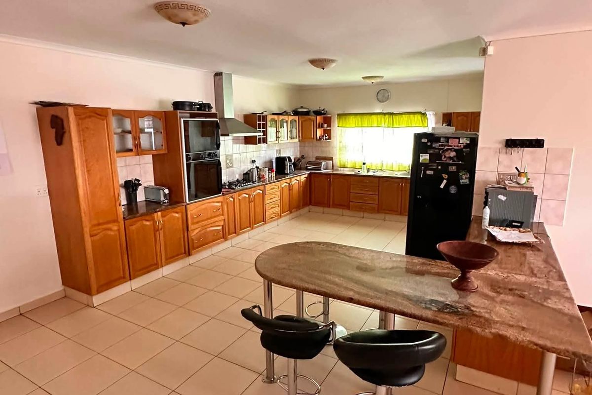 Spacious kitchen featuring wooden cabinetry, granite countertops, a breakfast bar, and built-in appliances, offering a functional layout with ample storage and workspace.