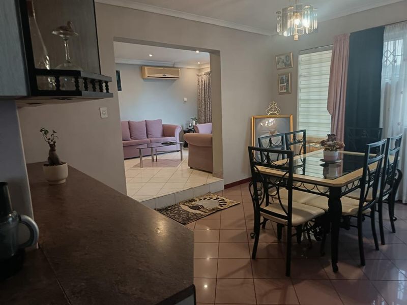 Open-plan dining and living area featuring tiled flooring, recessed lighting, and a wall-mounted air conditioning unit.