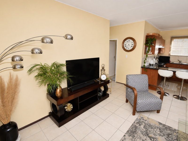 An open-plan living and kitchen area featuring tiled flooring, a breakfast bar, and functional kitchen cabinetry.