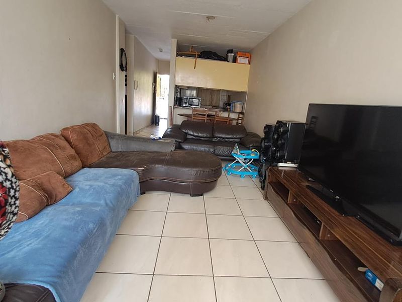 Open-plan living area featuring ceramic floor tiles and a connected kitchen space with built-in cabinetry.