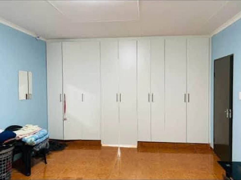A bedroom featuring extensive floor-to-ceiling built-in wardrobes and tiled flooring.