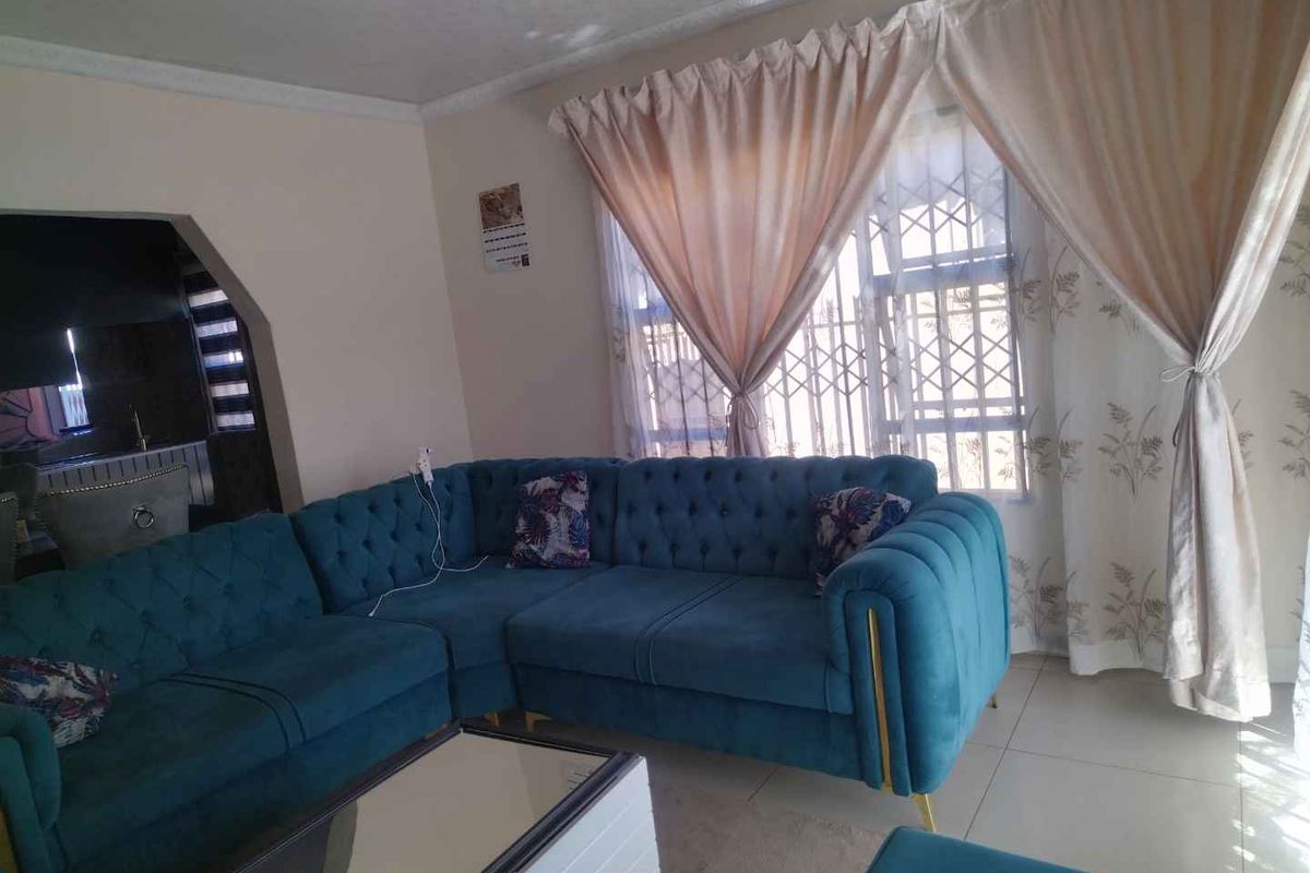 A living room featuring tiled flooring, an arched entryway leading to an adjacent space, and a window fitted with a security gate.