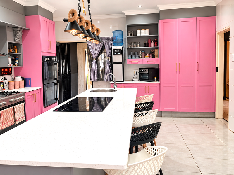 Modern kitchen featuring a large central island with quartz countertops, built-in cabinetry, integrated appliances, and stylish pendant lighting.