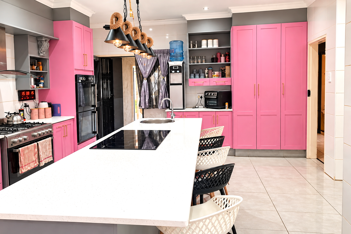 Modern kitchen featuring a large central island with quartz countertops, built-in cabinetry, integrated appliances, and stylish pendant lighting.