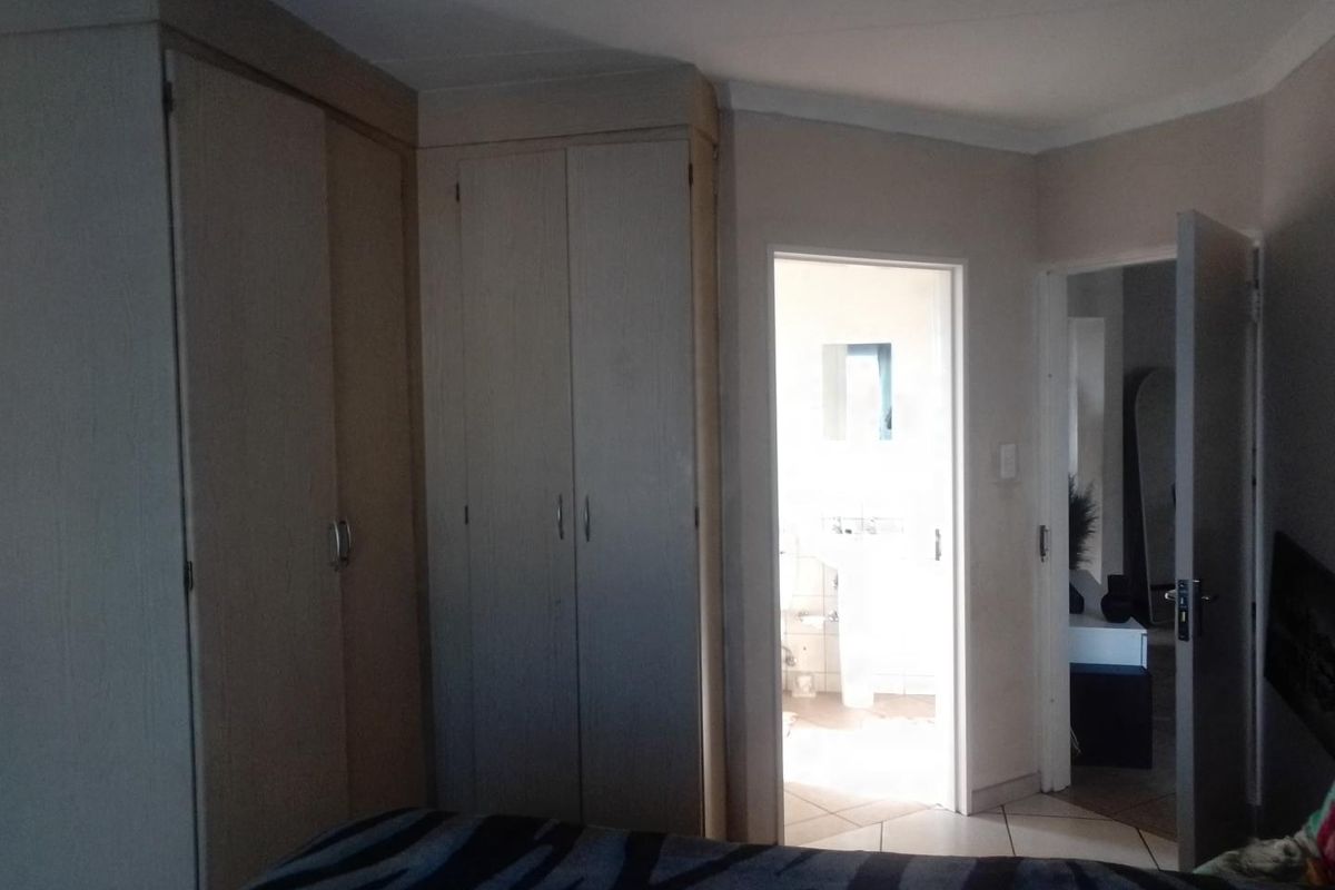 A bedroom featuring built-in wooden cupboards with a doorway leading to an adjacent bathroom.
