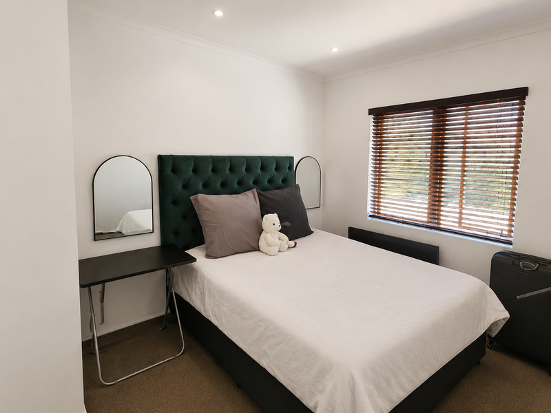 A well-maintained bedroom featuring neutral walls, carpeted flooring, recessed downlighting, and venetian blinds for natural light control.