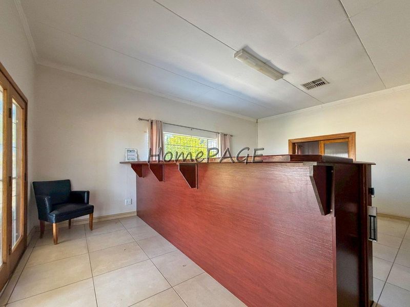 A dedicated bar area featuring a large built-in wooden counter, tiled flooring, and direct access to the outdoors via sliding glass doors.