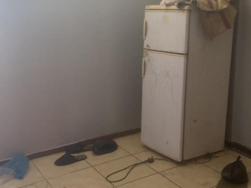 A basic kitchen area featuring tiled flooring and a high-level window, currently in need of cosmetic updates and maintenance.
