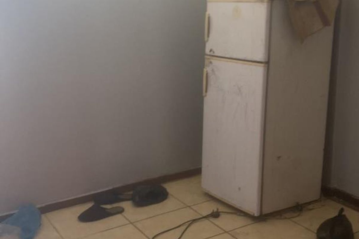 A basic kitchen area featuring tiled flooring and a high-level window, currently in need of cosmetic updates and maintenance.