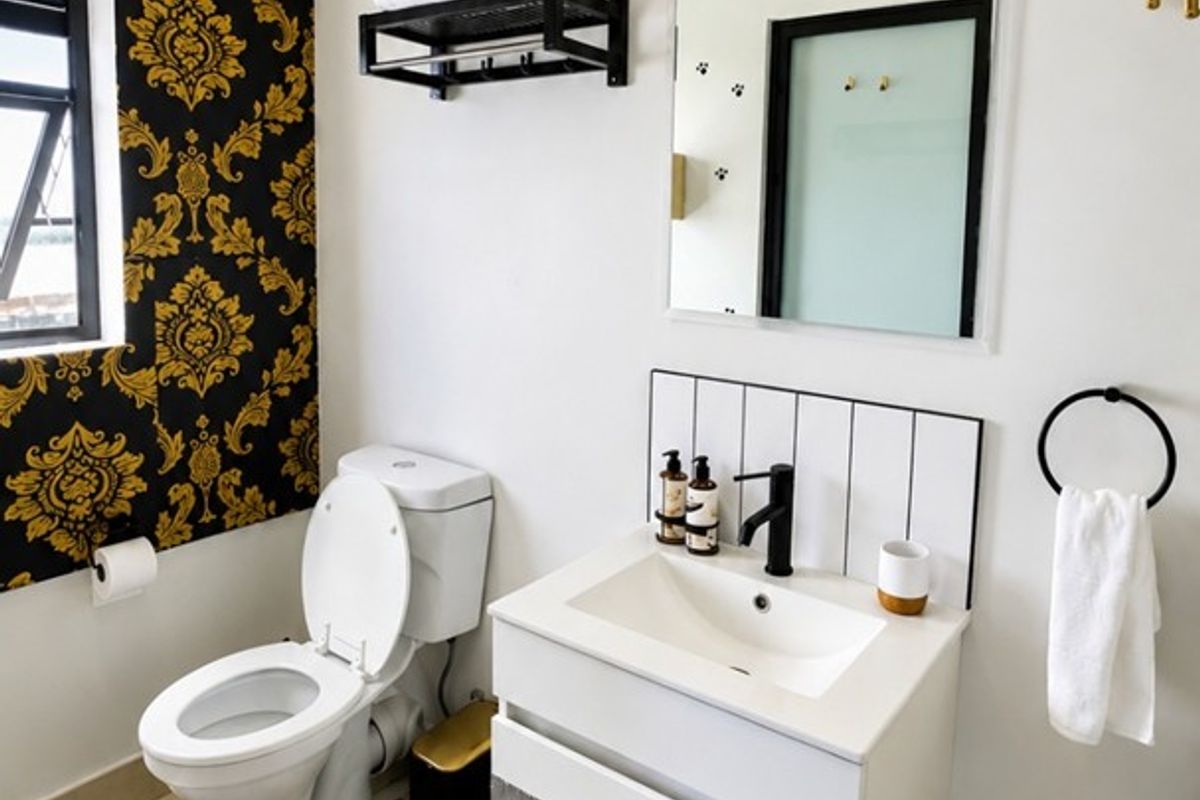 A modern bathroom featuring a wall-mounted vanity with a black mixer tap, a toilet, and decorative wallpaper accents.