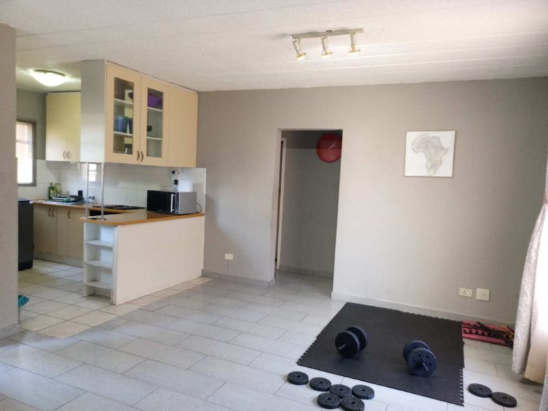 Open plan living area featuring tiled flooring and an adjoining kitchen with built-in cabinetry and a peninsula counter.