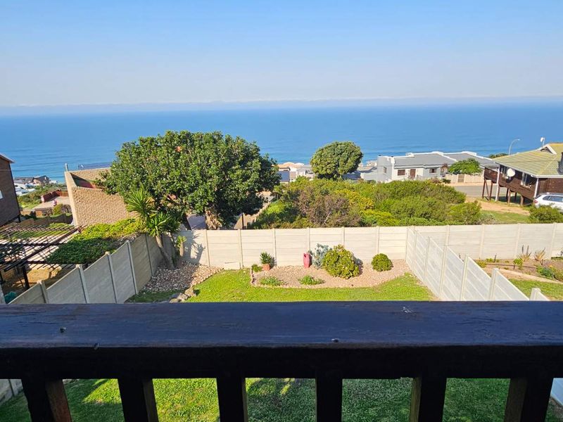 Elevated view overlooking a residential garden, precast boundary walls, and the ocean horizon.