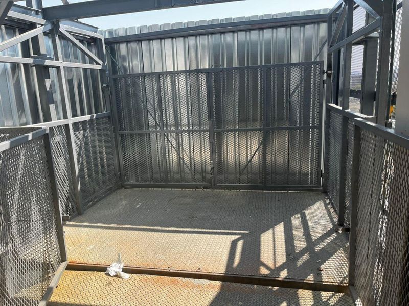 A secure, industrial-style utility enclosure featuring metal mesh walls, a metal gate, and a durable metal floor.