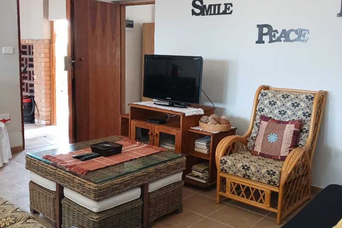 A living room featuring tiled flooring and access to an adjacent utility area through a wooden door.