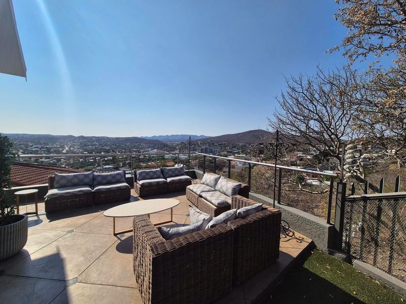 Spacious outdoor balcony featuring a glass balustrade and panoramic city and mountain views, perfect for entertaining.