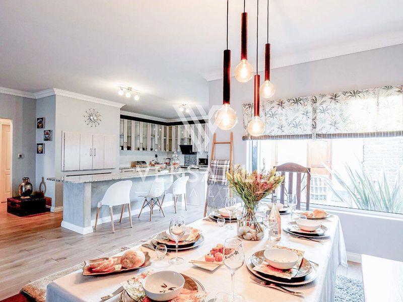 Spacious open-plan kitchen and dining area featuring a central island, modern pendant lighting, and neutral finishes, creating a bright and inviting living space.