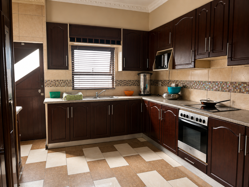 A functional kitchen featuring dark wood cabinetry, mosaic tile backsplash, built-in oven, electric cooktop, and tiled flooring with direct access to an exterior door.