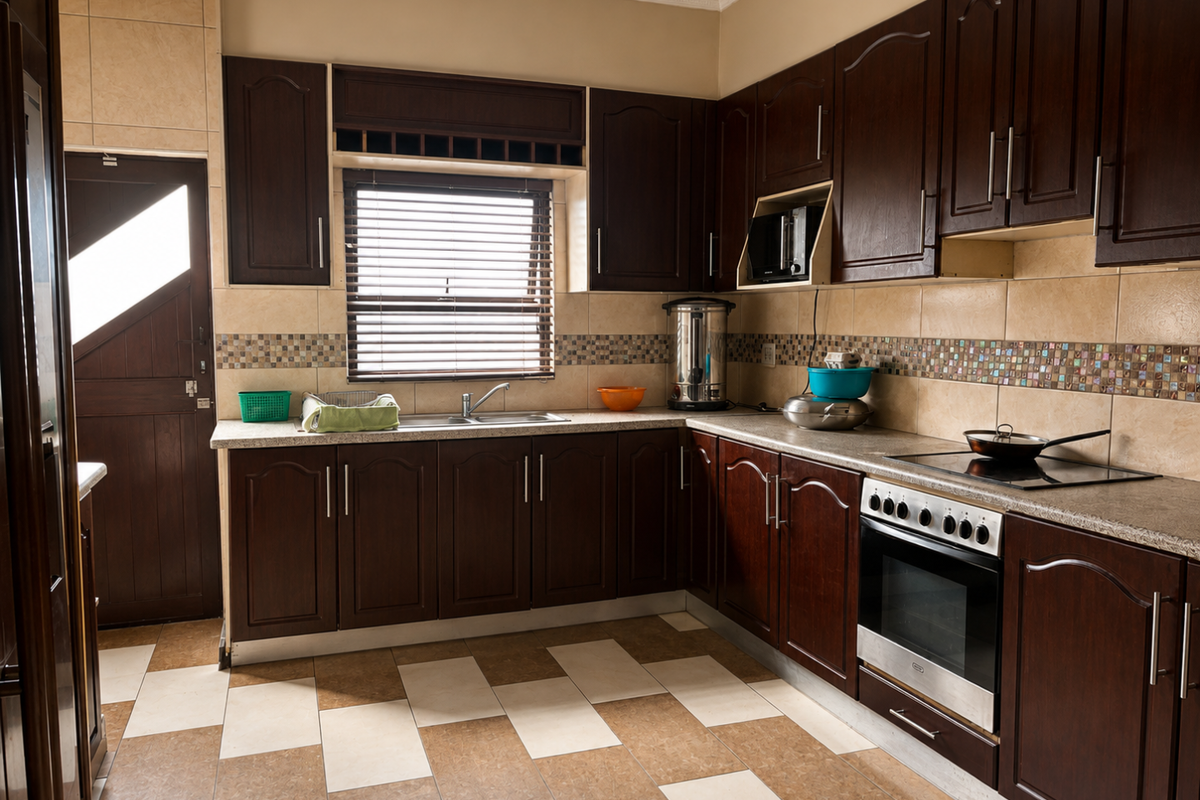 A functional kitchen featuring dark wood cabinetry, mosaic tile backsplash, built-in oven, electric cooktop, and tiled flooring with direct access to an exterior door.