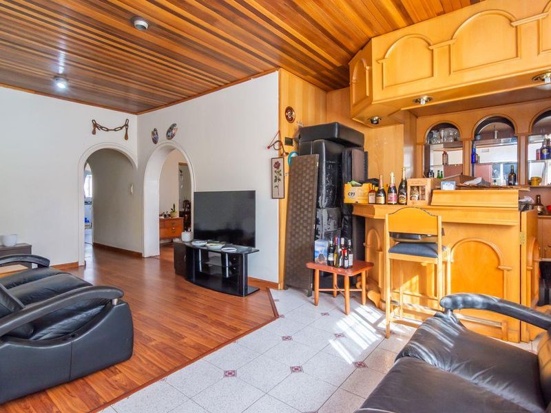 A living area featuring a built-in wooden bar, timber-clad ceiling, and arched doorways connecting to adjacent rooms.