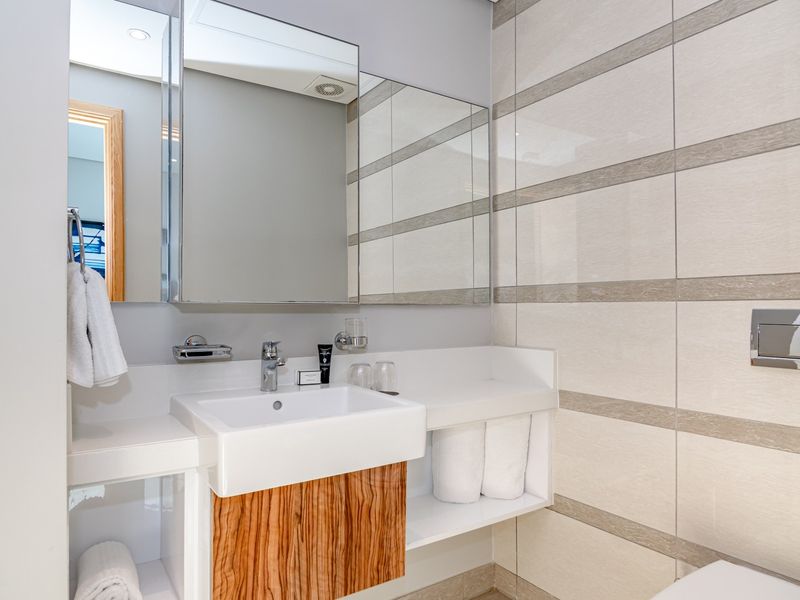 Modern bathroom featuring a sleek wall-mounted vanity with integrated basin, mirrored medicine cabinet, and contemporary ceramic wall tiling.