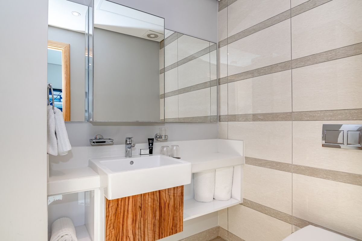Modern bathroom featuring a sleek wall-mounted vanity with integrated basin, mirrored medicine cabinet, and contemporary ceramic wall tiling.